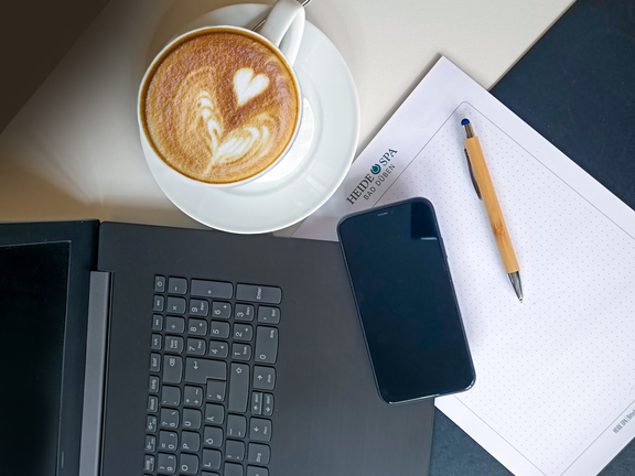 Laptop und Handy im Tagungsraum mit Tasse Kaffee und Schreibutensilien
